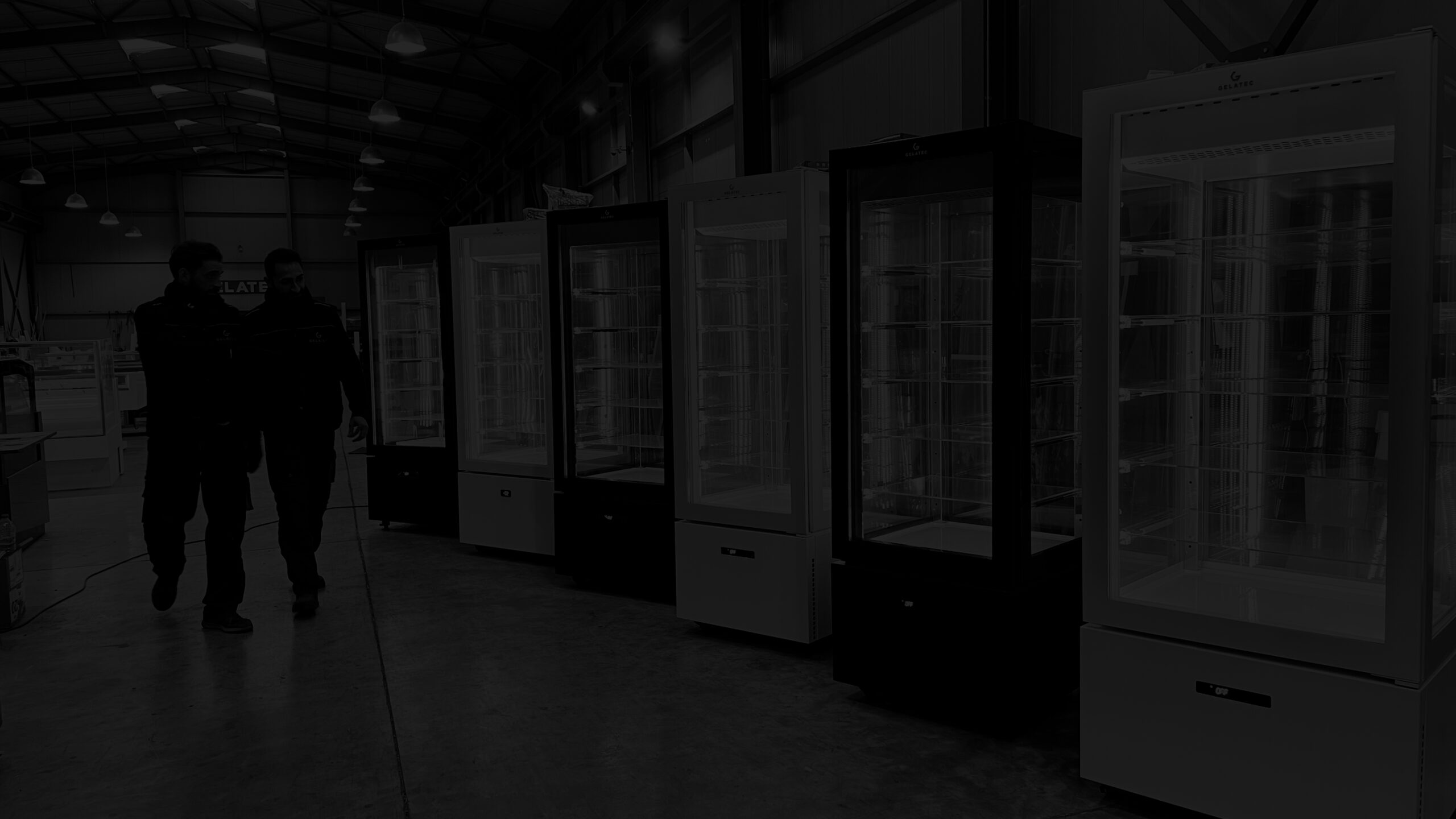 GELATEC team members walking alongside upright showcases in the factory