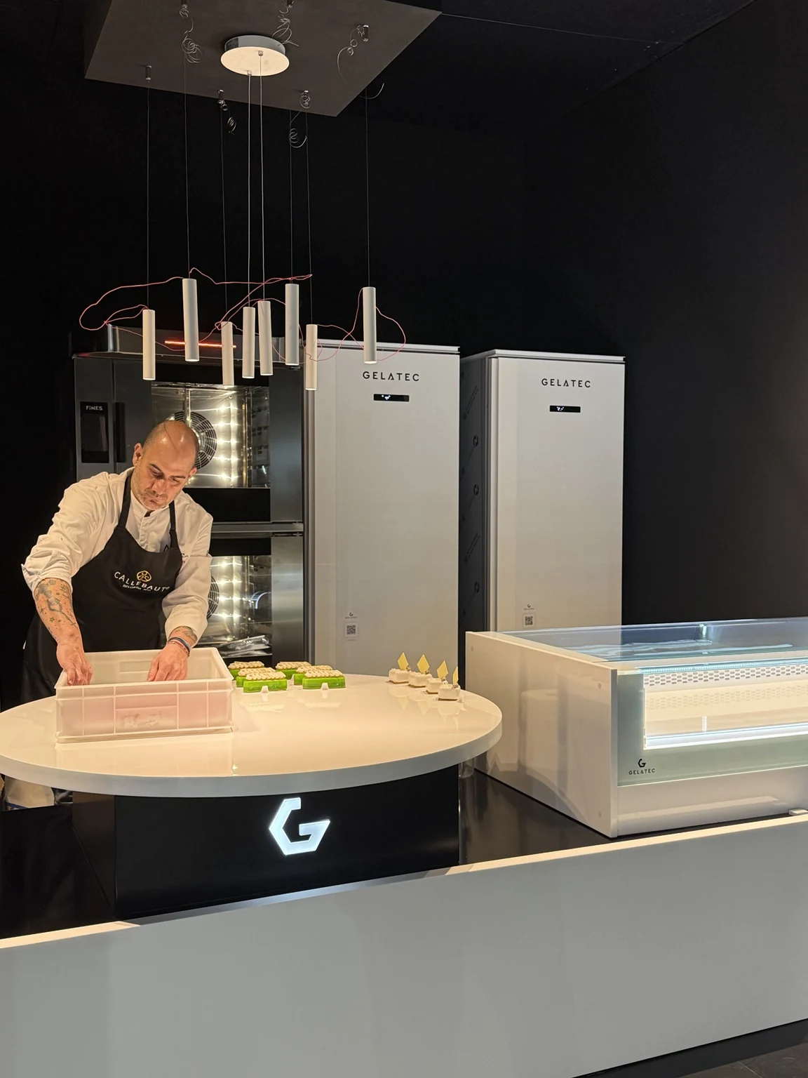 | GELATEC - Инновационные витрины Gelato Профессиональный кондитер на работе рядом с холодильным оборудованием GELATEC